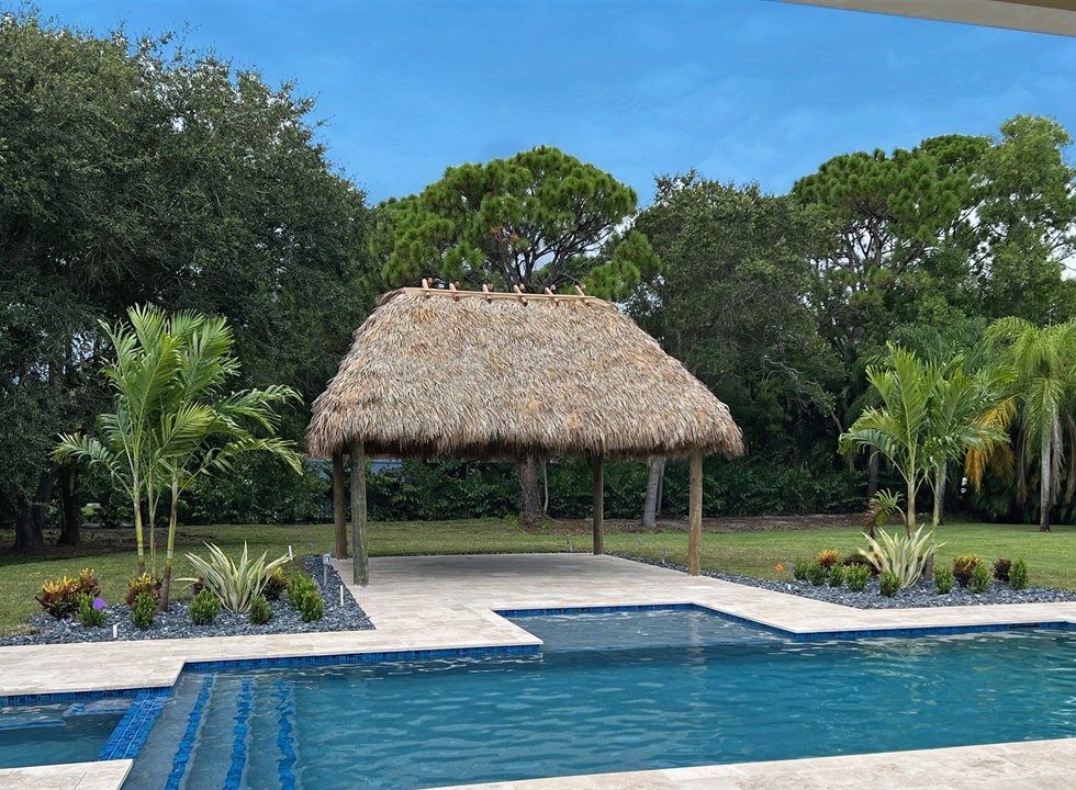 Pool with tropical landscaping and thatched shade